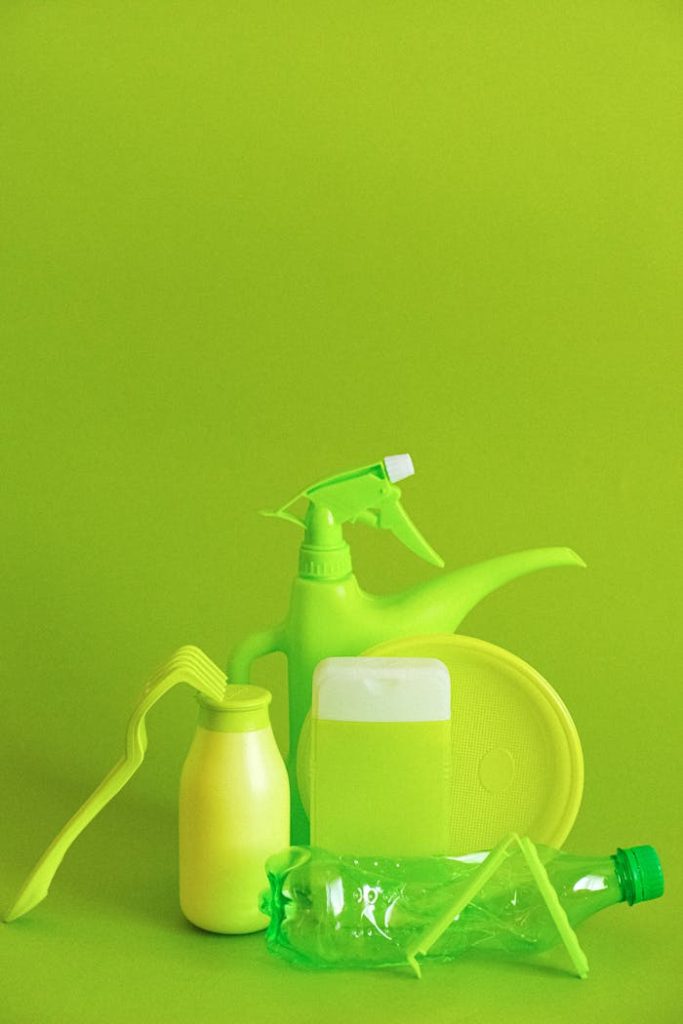 Set of assorted plastic containers for liquids with plate placed on green background
