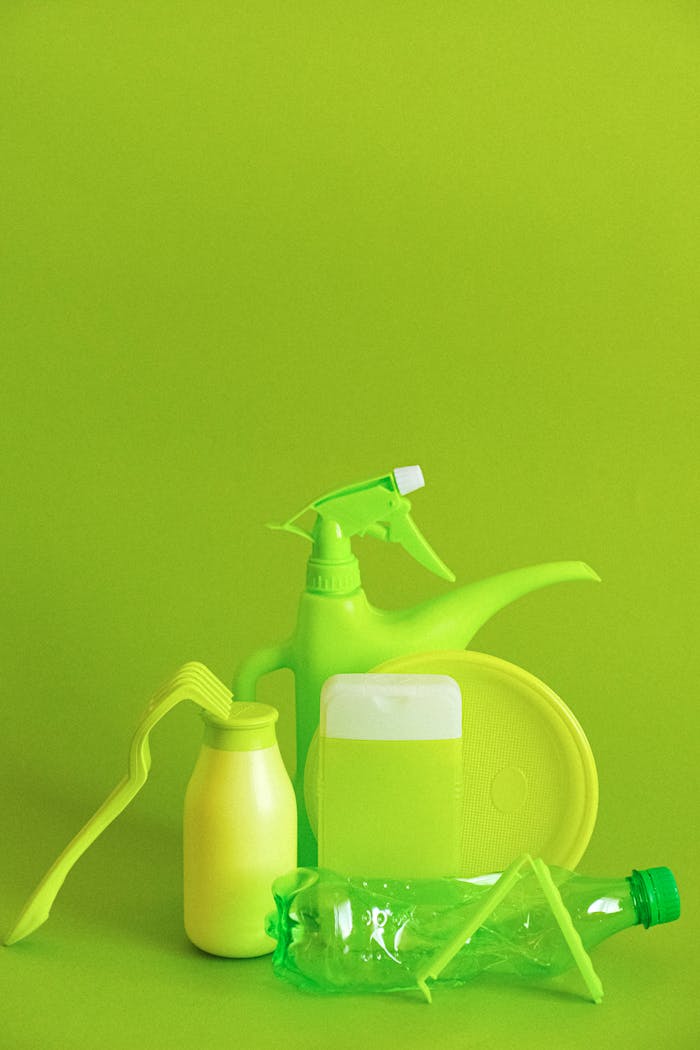 Set of assorted plastic containers for liquids with plate placed on green background