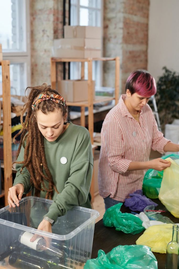 Two women sorting recycling, organizing plastic and glass indoors.